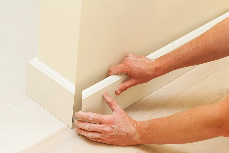 Worker installing baseboard trim
